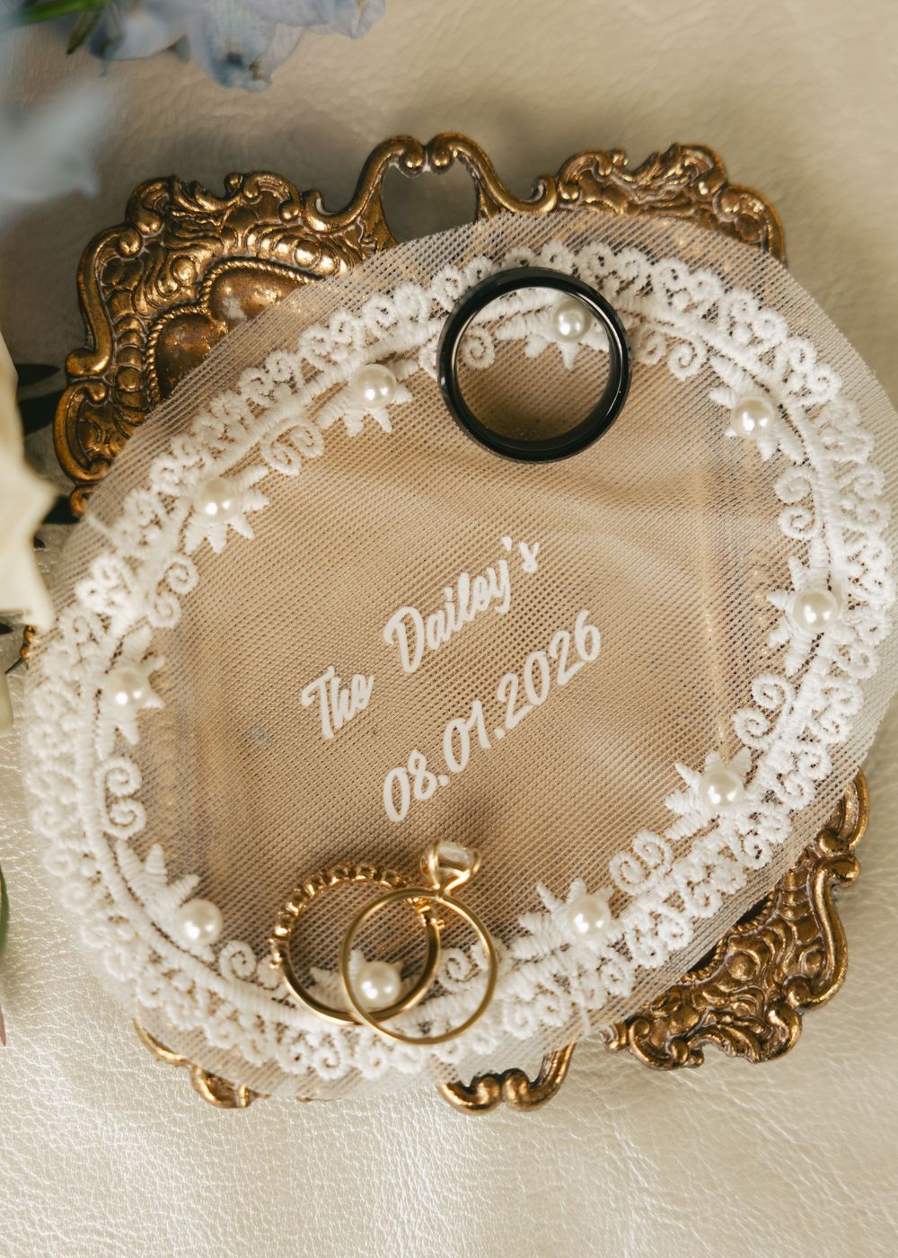 Elegant lace ring bearer pillow with gold frame displaying The Daileys 08.01.2026 wedding date with rings.