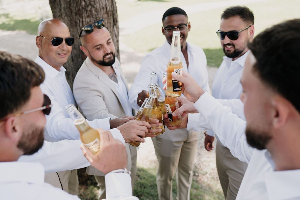 Friends of the groom toast with beer during wedding preparations at Villa Nobel