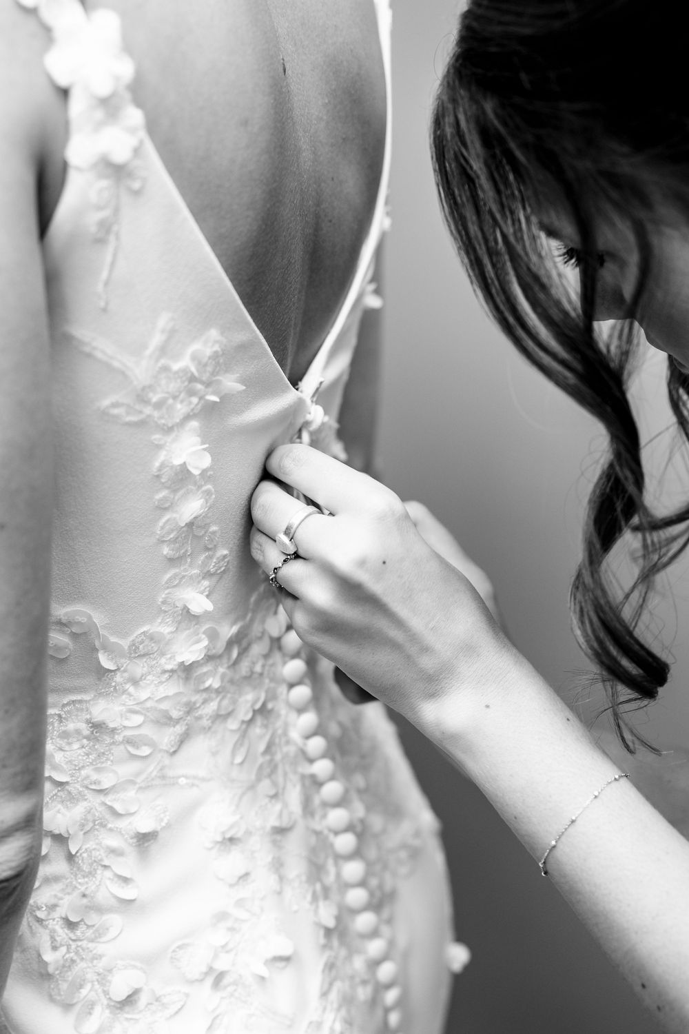 Close-up black and white photo series showing intricate lace and beading details on a wedding dress.