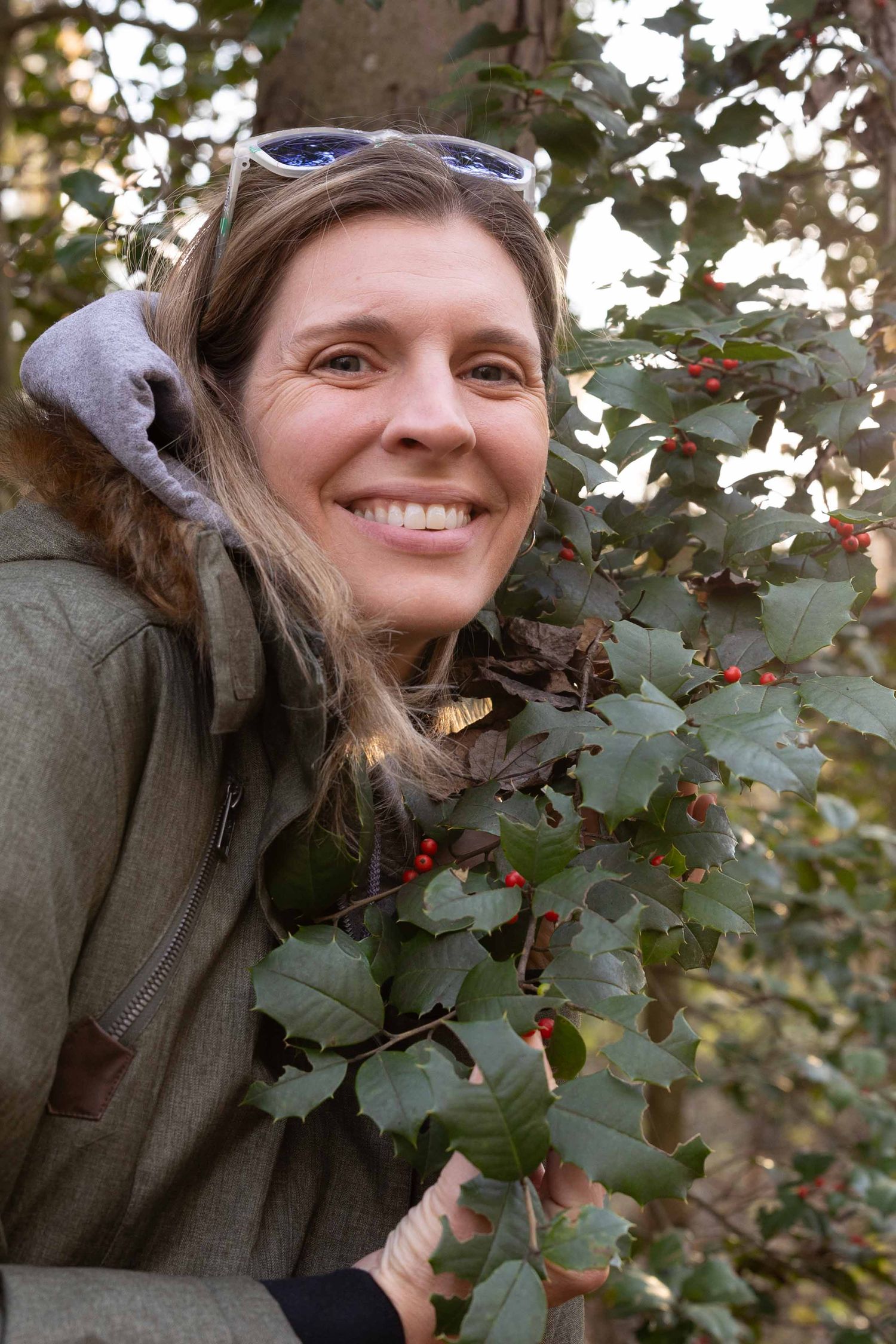 Someone smiles while picking berries from a bush in an autumn garden setting.