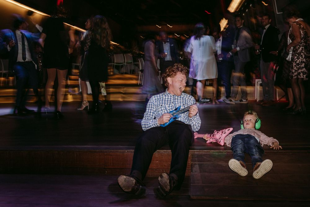 Two young guests resting on dance floor during evening wedding reception.