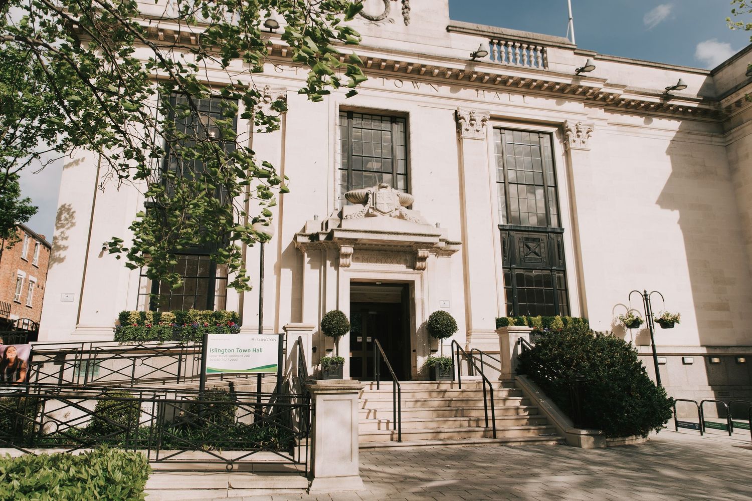 Islington Town Hall neoclassical building entrance with white columns, topiary bushes, and stone steps in an urban setting on wedding day.
