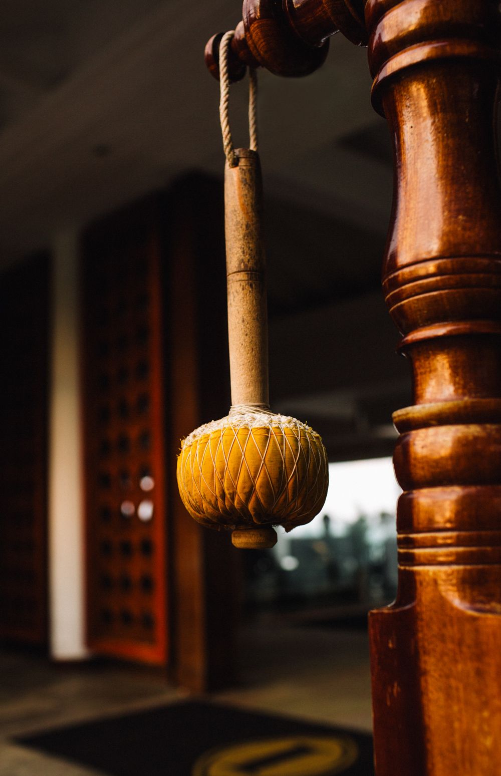 Close-up of traditional wooden architectural detail with hanging wooden gong at InterContinental, atmospheric cultural texture and depth.