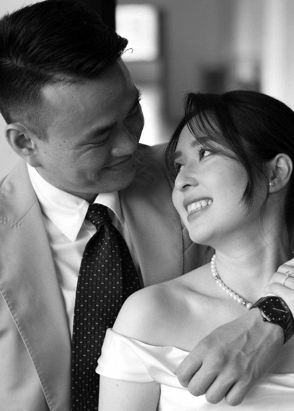 Black and white portrait of smiling Asian couple sharing a tender intimate moment together indoors.