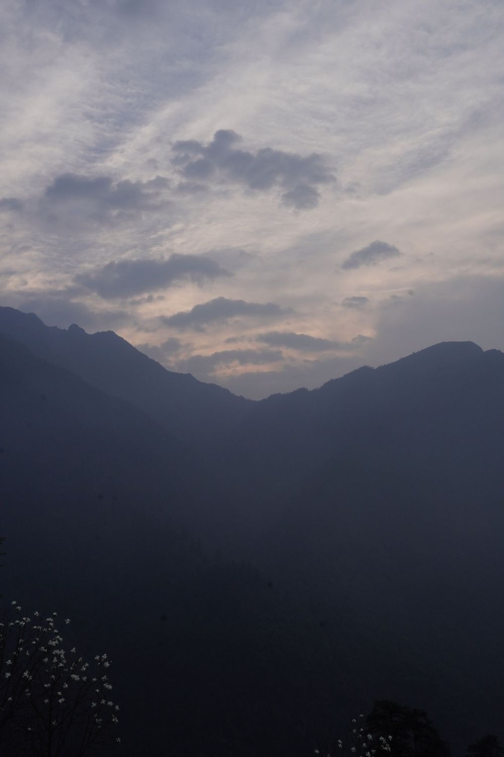 Layers of mountain ridges disappearing into the twilight haze, a study in minimalist nature and silent storytelling.