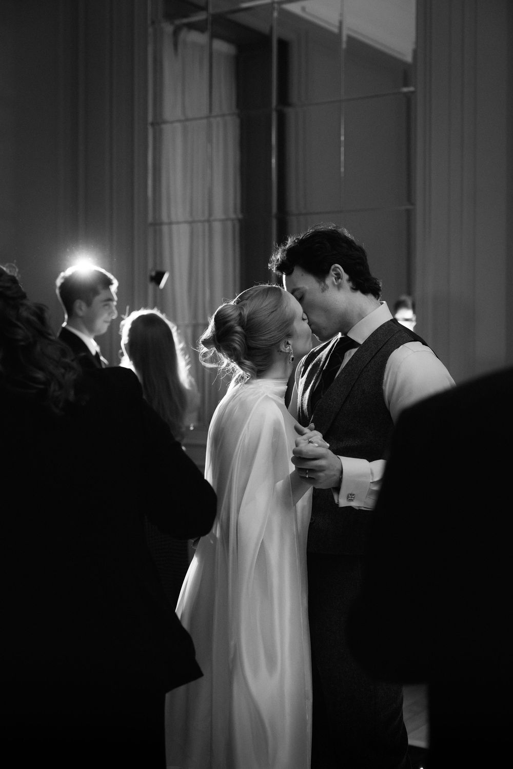 A black and white photo sequence shows a couple sharing their first kiss as newlyweds during a wedding ceremony.