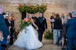 A panoramic view of a wedding reception in a rustic brick venue with guests mingling and dancing.