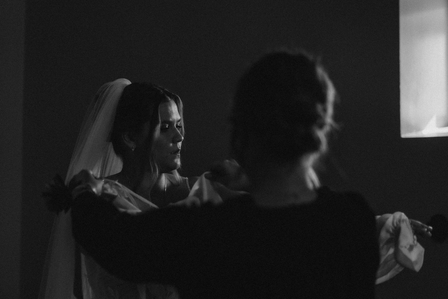 bride getting ready in soft window light inside church cinematic documentary wedding photography