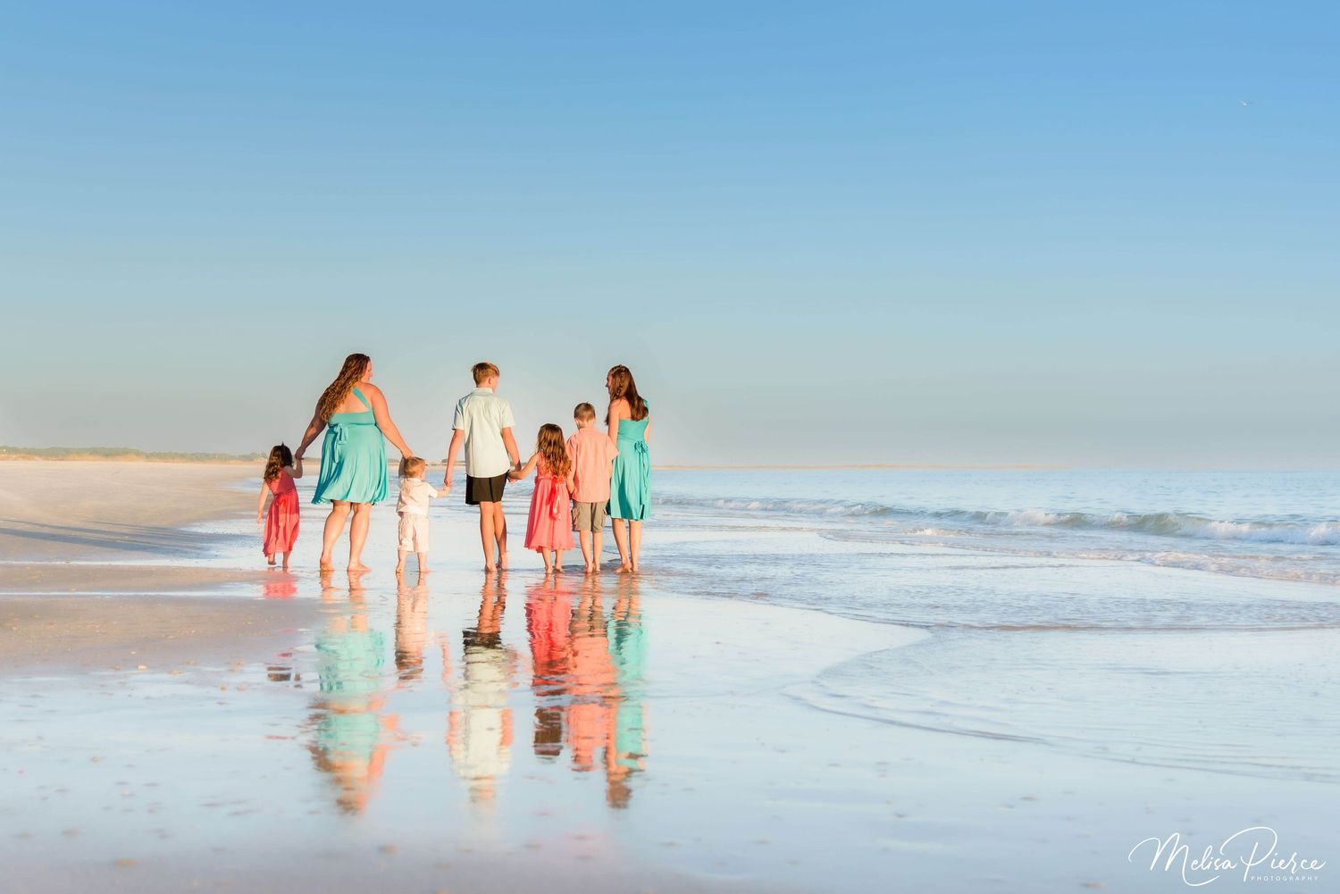 Family walking along the shoreline during a Dauphin Island sunrise beach photography session with soft golden light and calm Gulf waves.