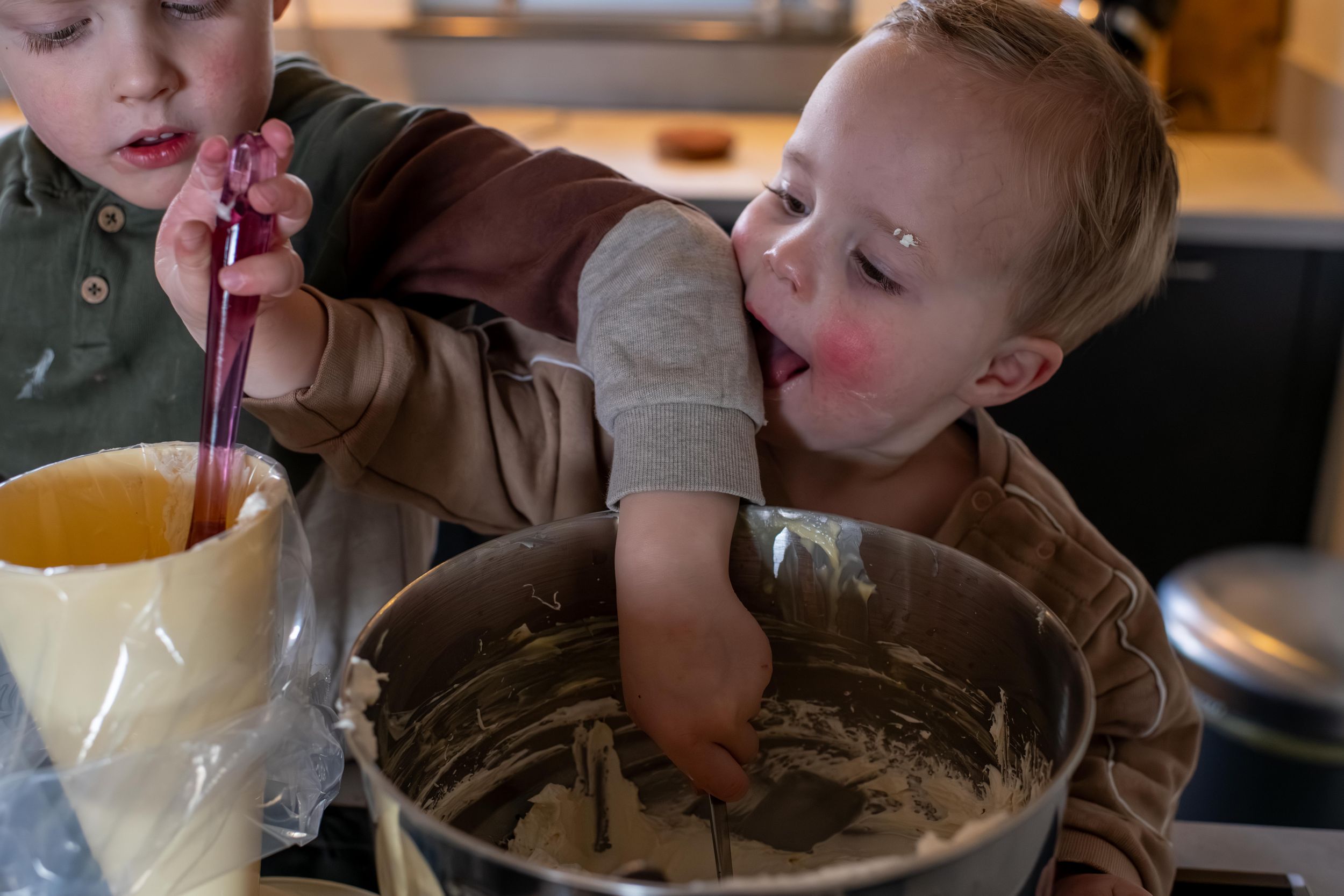 A person sips chocolate milkshake through a straw while sitting at a wooden table in a restaurant.