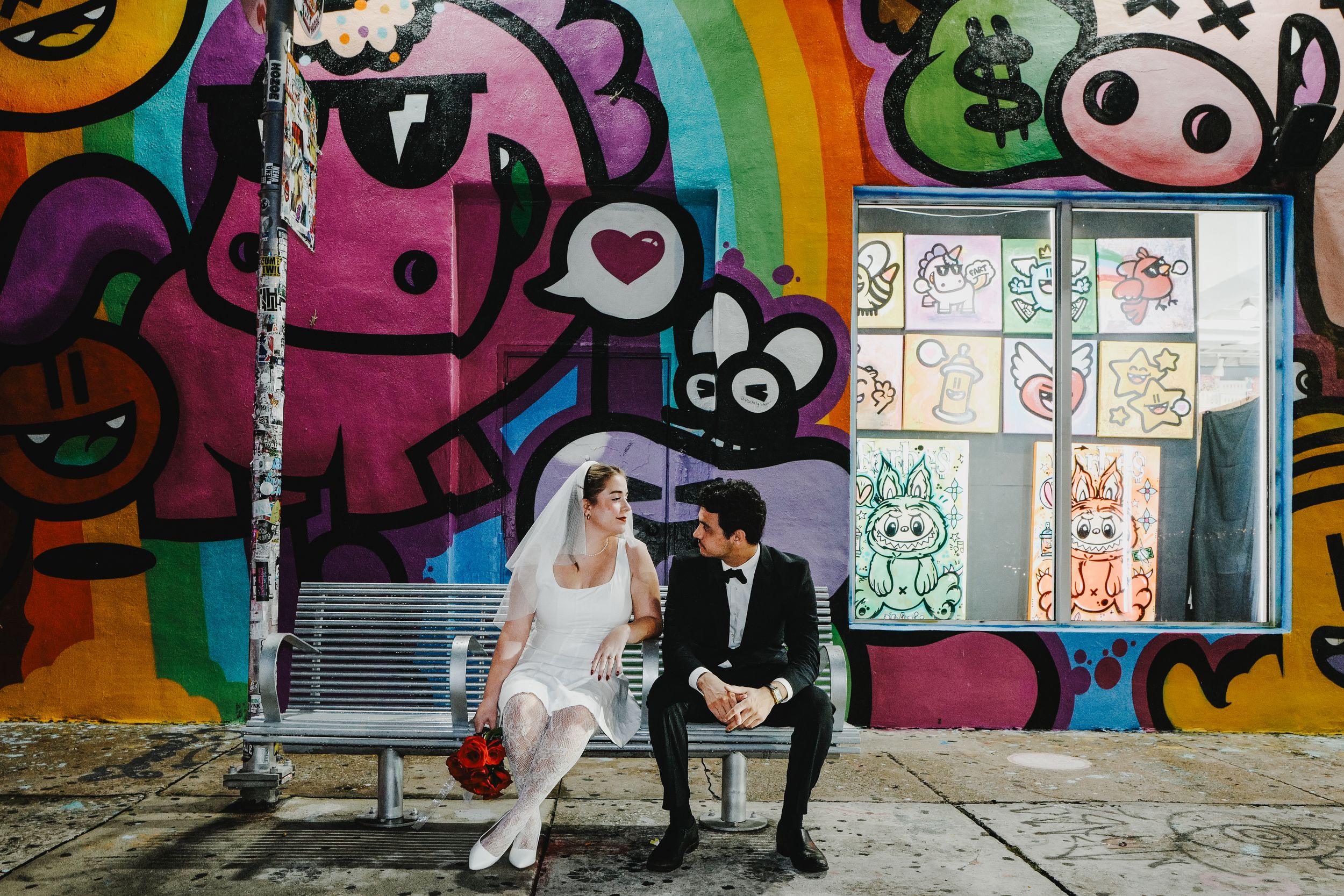 A romantic wedding portrait of a couple in elegant attire sharing a tender moment beneath trees at dusk.