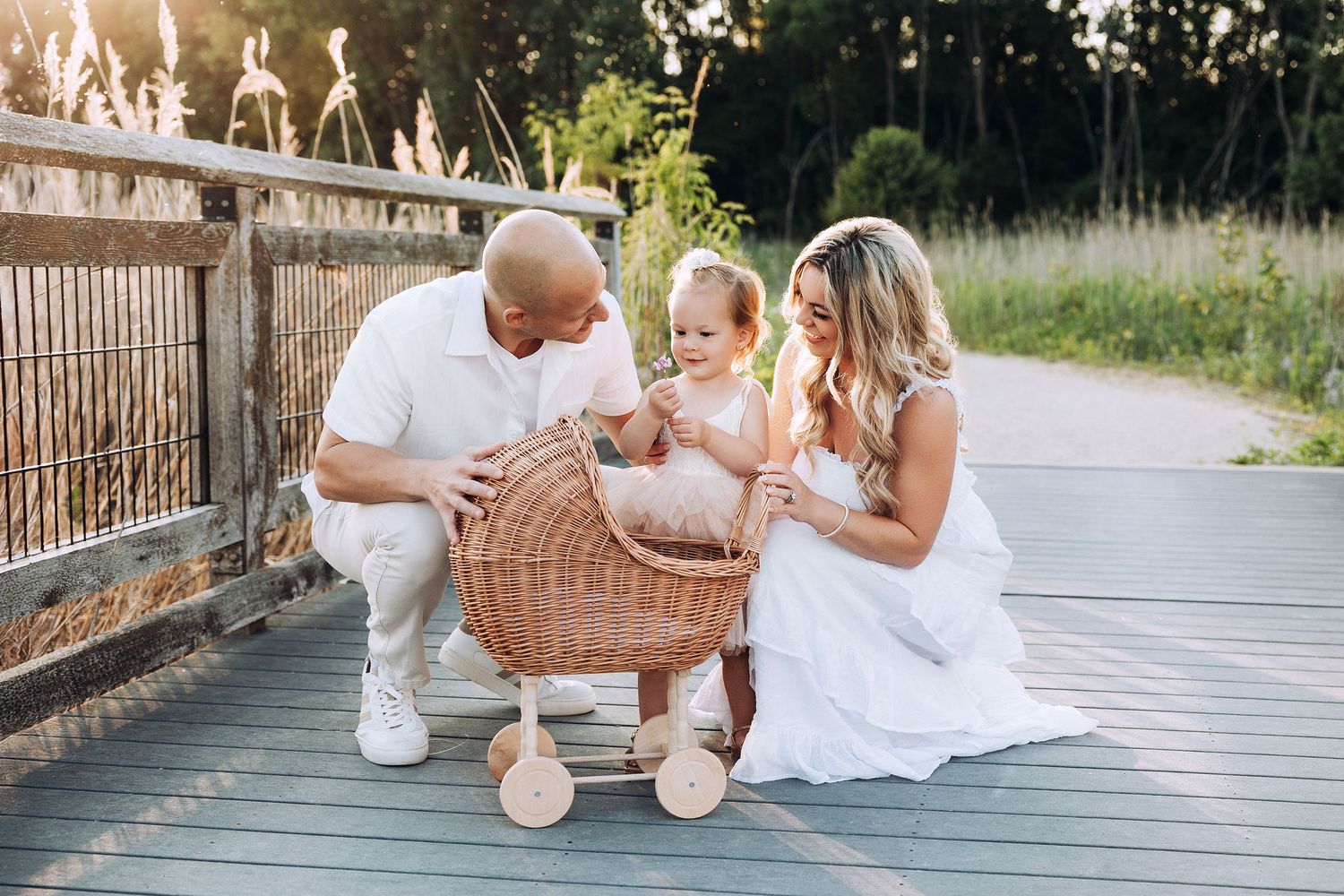 family of three and baby playing with a toy stroller
