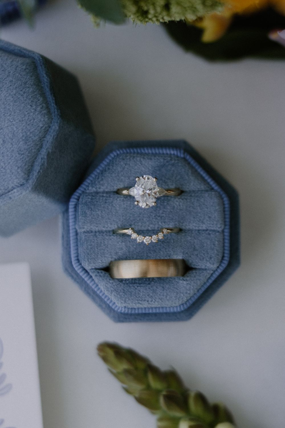 Diamond engagement ring in light blue velvet ring box with greenery accents.