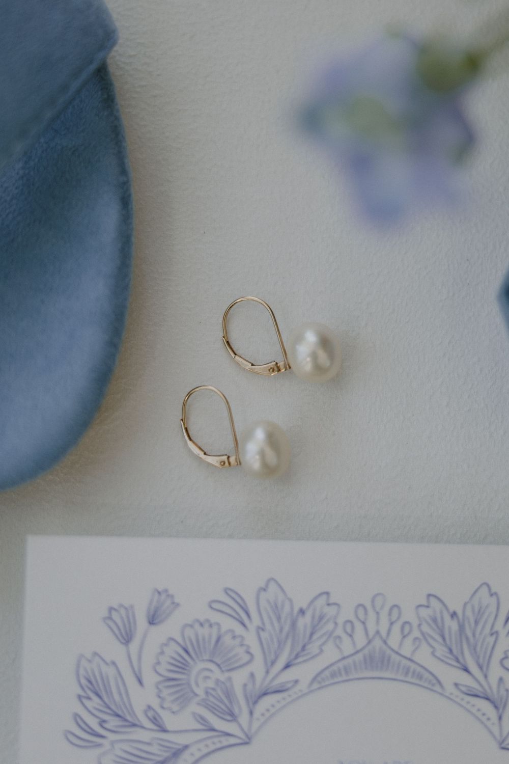 Pearl drop earrings and delicate floral stationery details.
