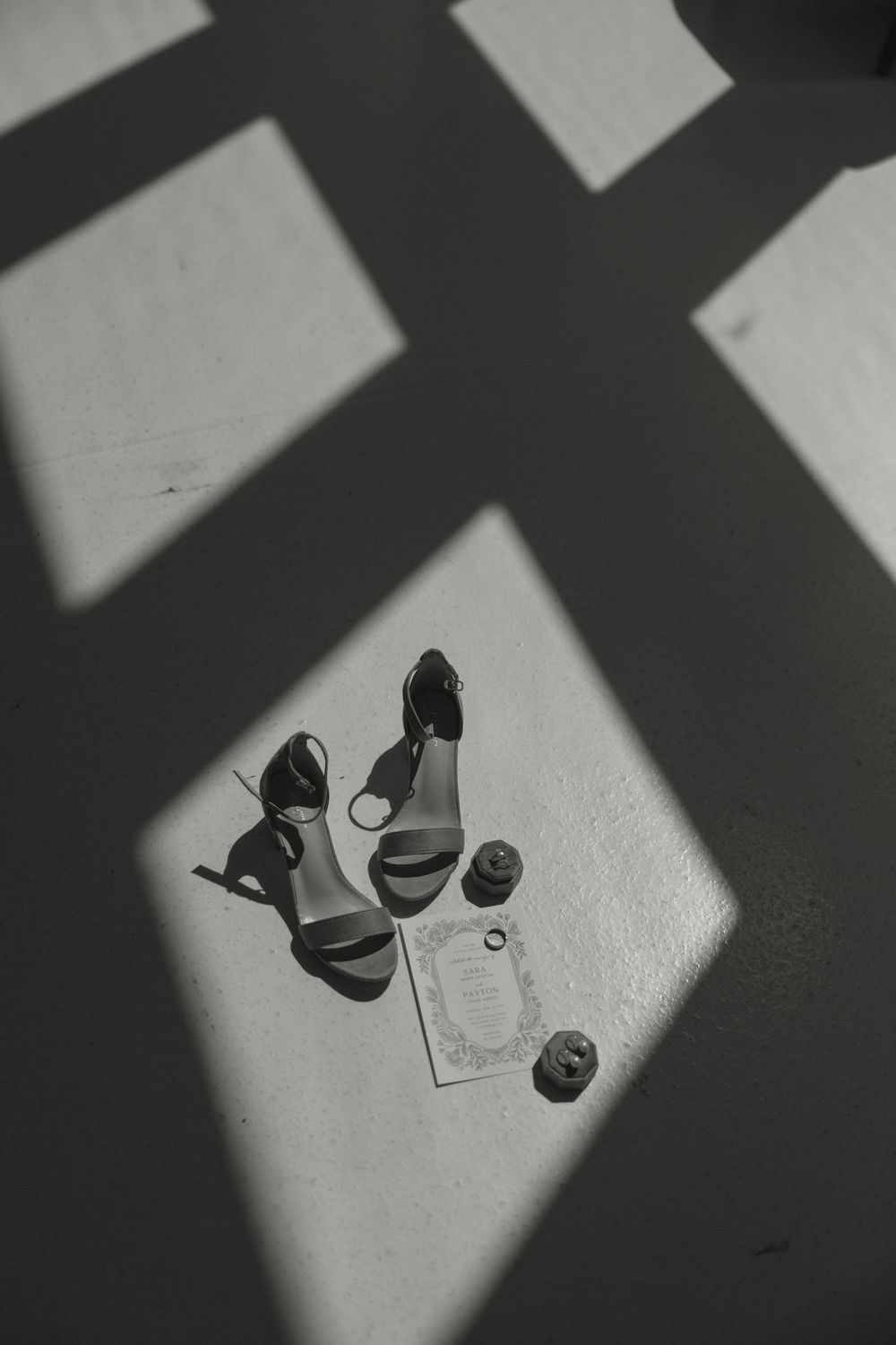 Artistic black and white shadow composition of wedding shoes on light floor.
