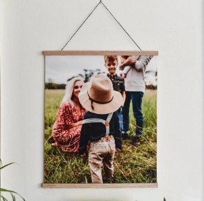 Family portrait hanging on wall showing outdoor scene with child in hat.
