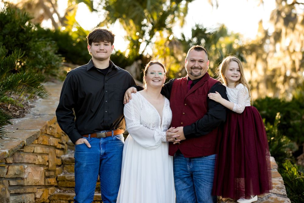 Family members stand together outdoors in coordinating outfits during golden hour for a portrait session.
