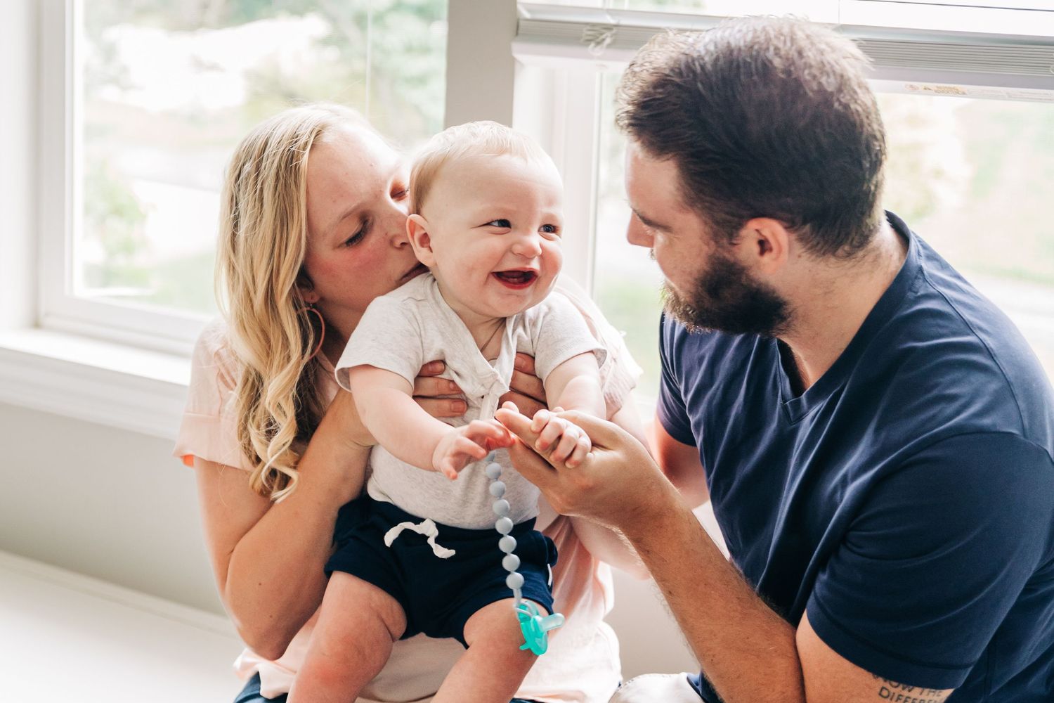 A family shares joyful moments together during an indoor lifestyle photoshoot with natural lighting.