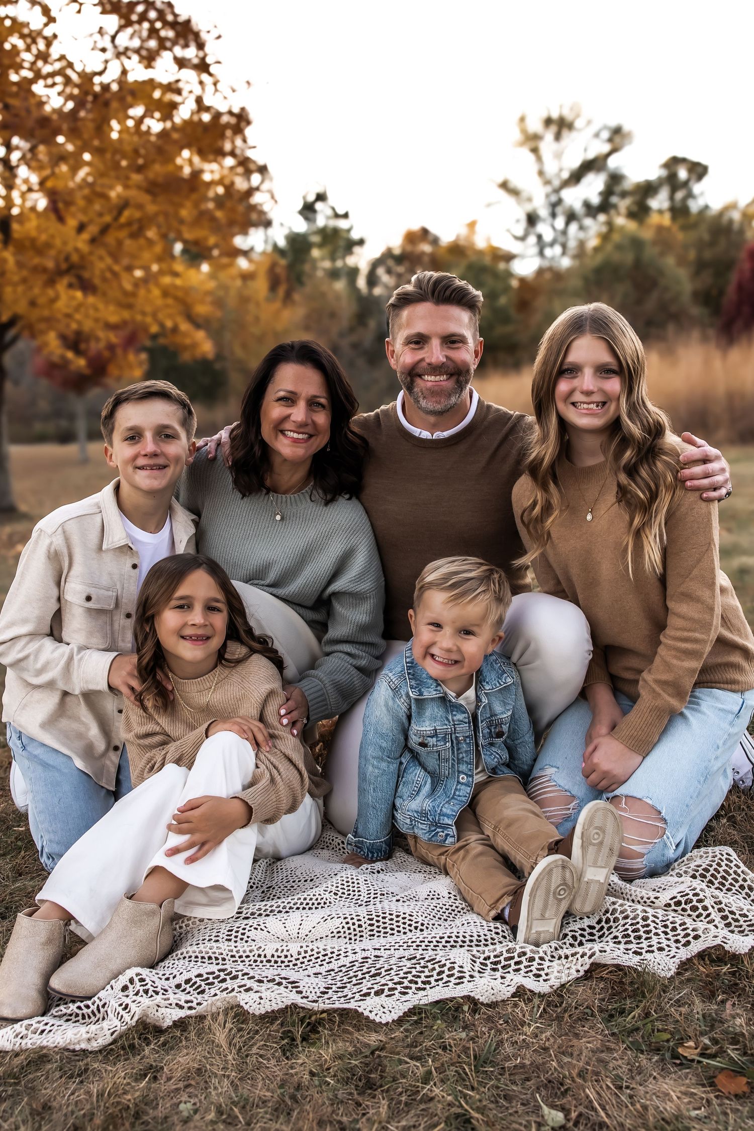 Family of six smiling in a park during their family photo session, in the fall in Central Indiana.