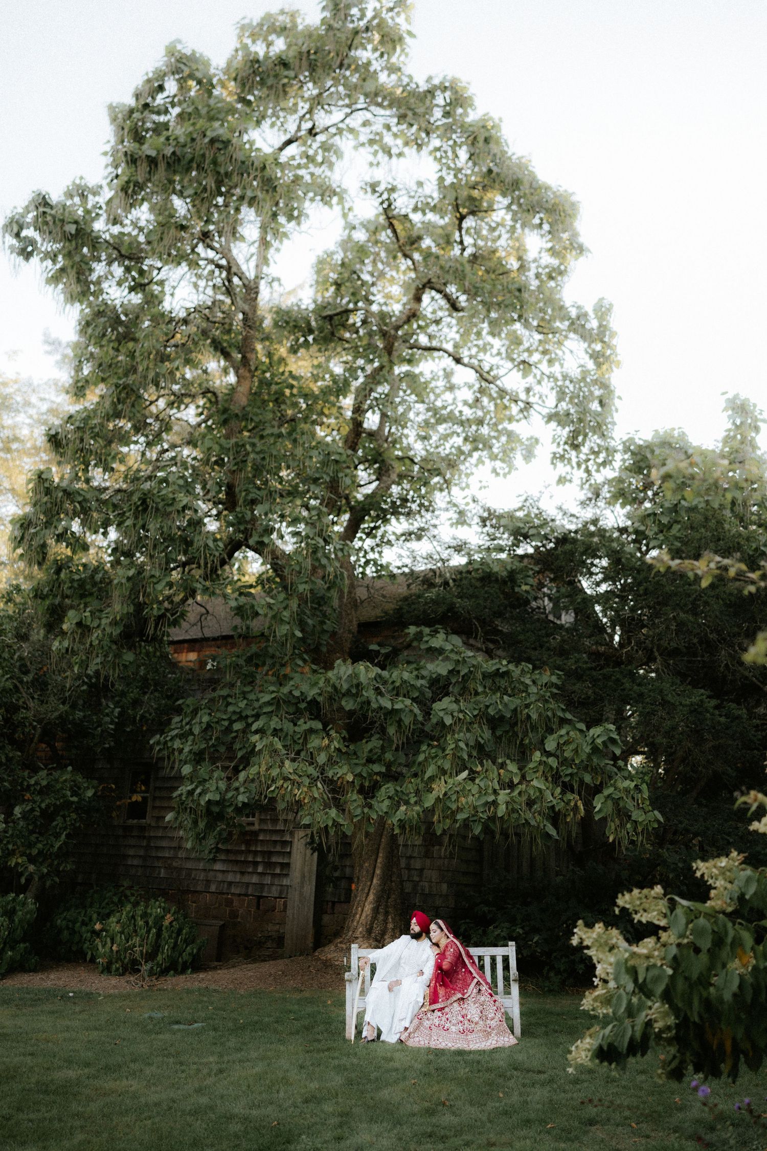 Wedding ceremony setup with white drapes and couple in traditional Indian attire.