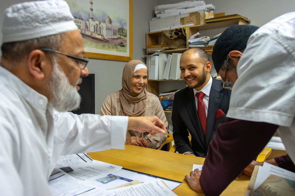 Group of Muslim professionals meeting around a desk in an office, engaged in a friendly discussion.