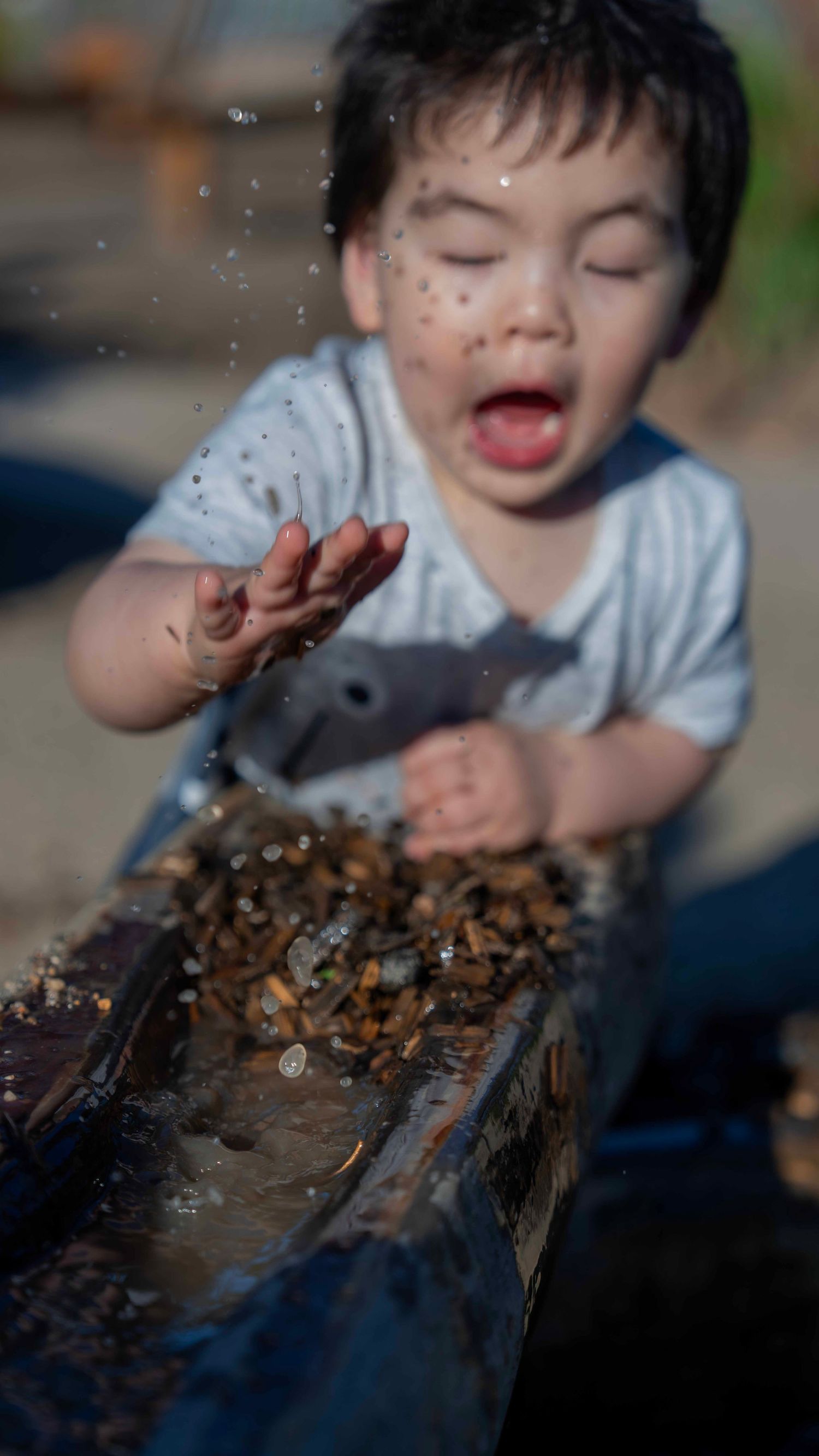 Child playing and splashing in mud with pure joy on their face.