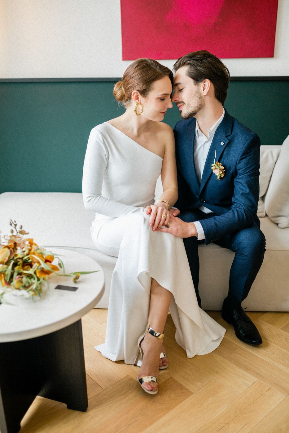 Intimate moment in modern setting with white and navy attire against green and red wall decor.
