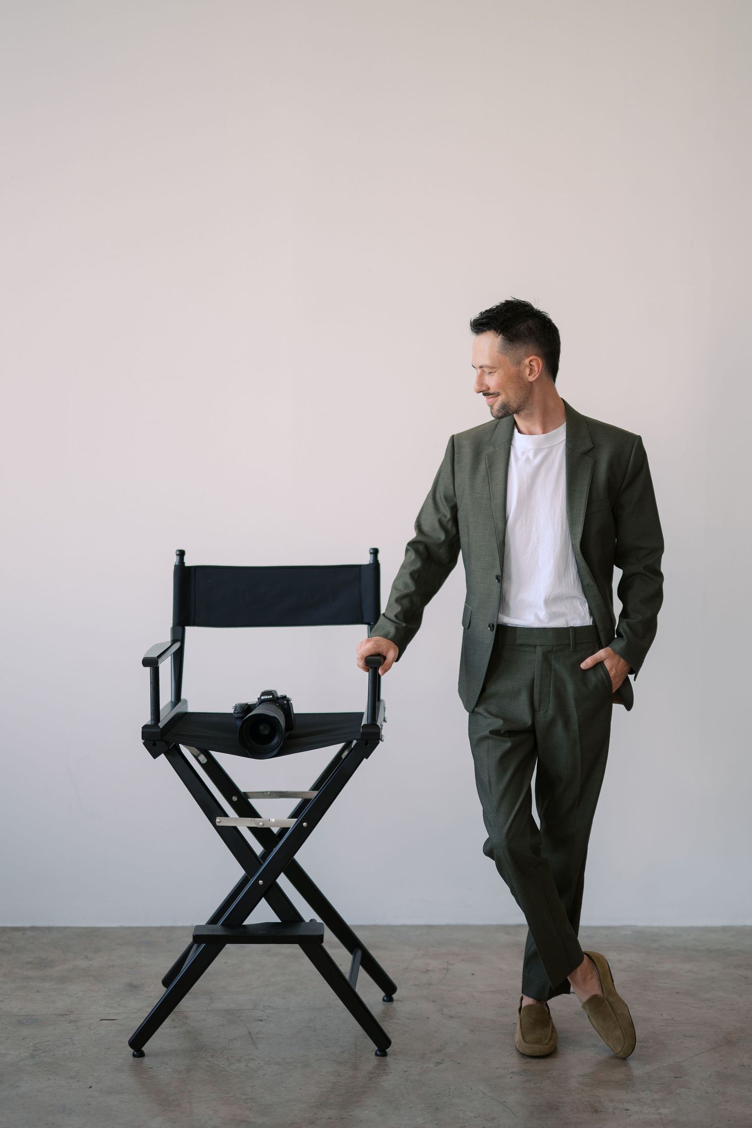 A series of five photos showing someone in a gray suit interacting with a black director's chair against a white backdrop.