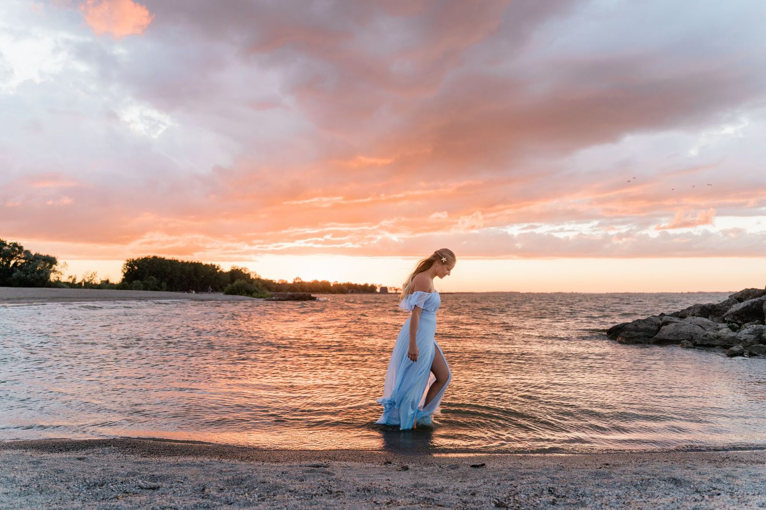A dramatic orange and pink sunset illuminates the ocean horizon at Maumee Bay State Park Beach during Toledo Senior Photo session
