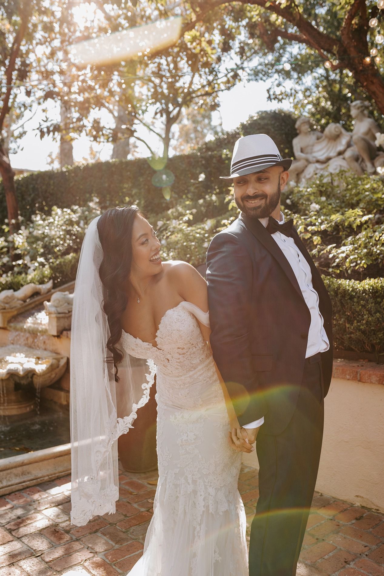 A bride and groom share a tender moment outdoors in golden sunlight with a flowing white veil at Rancho Bernardo Inn.