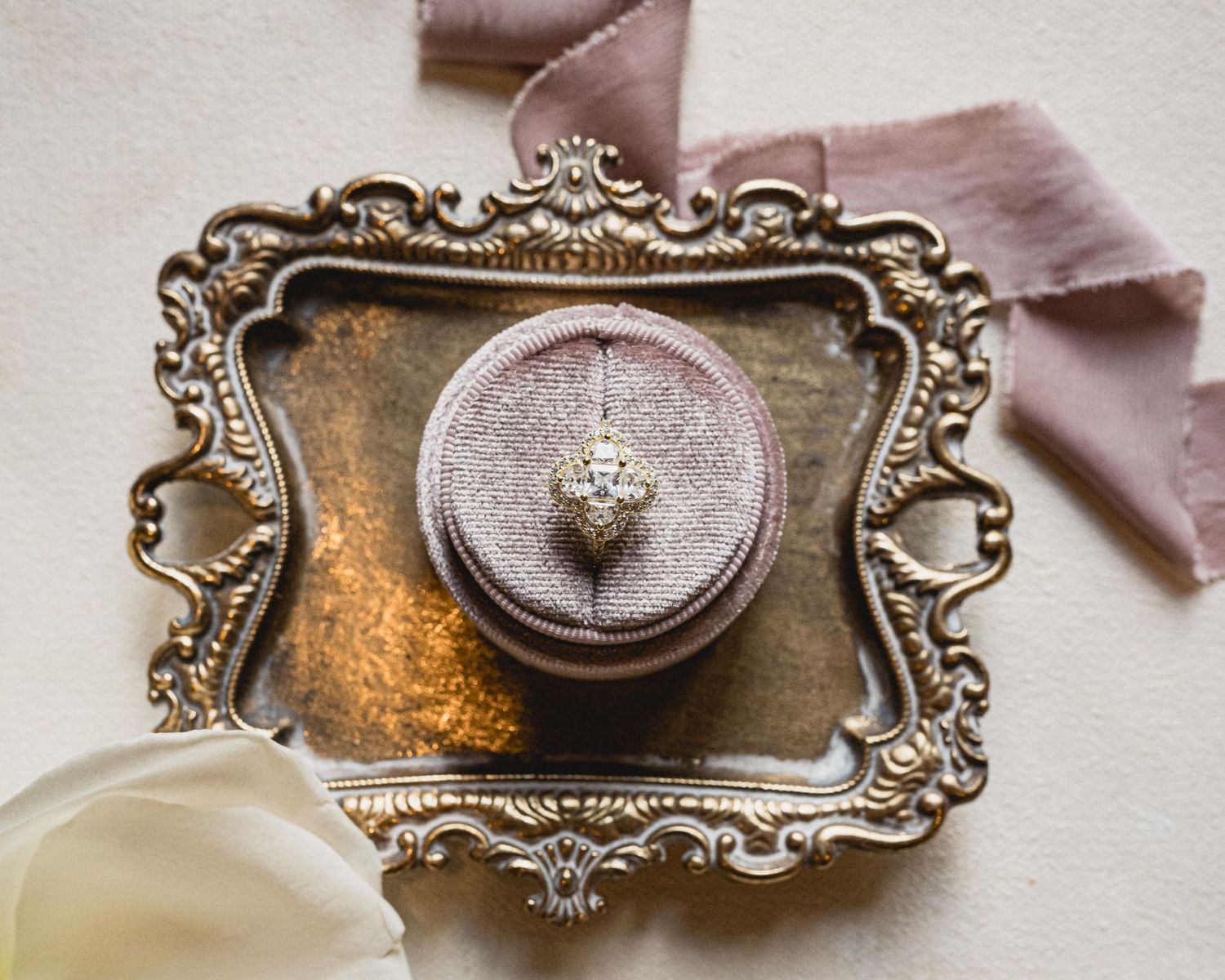 Ornate vintage silver trays and decorative items arranged in a horizontal line on a light beige surface.