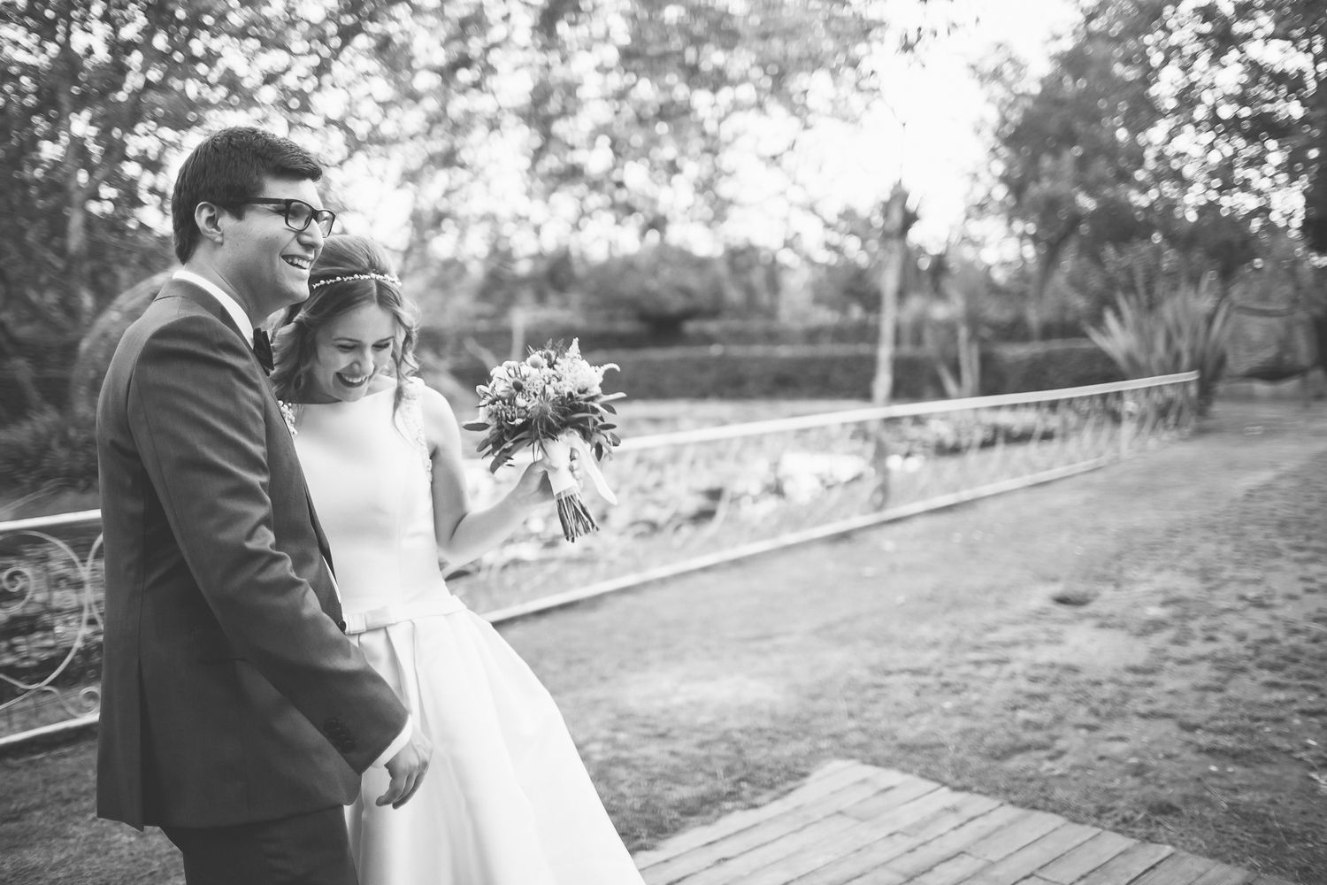 casal sorridente na quinta solar da levada durante a sessão. A noiva tem na mão o ramo e delocam.se para outro espaço
