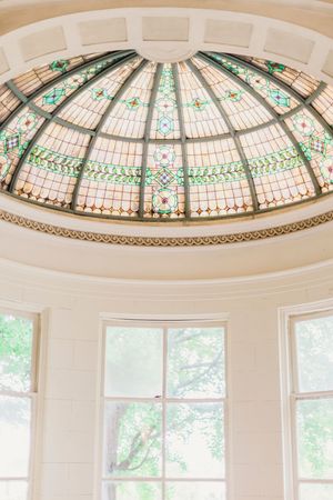 Ornate stained glass dome ceiling with green and white floral patterns in a Victorian-style architectural design.