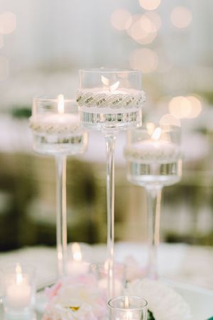 Elegant glass candleholders with tealights create a romantic atmosphere against a softly blurred background.
