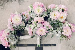 Pink and white floral bouquets with delicate baby's breath arranged on a textured gray background.