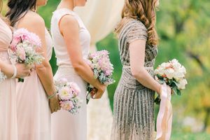 Elegant bridesmaids in blush pink and sparkling grey dresses hold delicate pink and white floral bouquets.