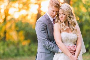 Romantic outdoor couple portraits with bride in lace gown and groom in grey suit amid golden autumn foliage.