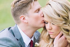 A tender moment between newlyweds captured in soft focus against a blurred green natural background.