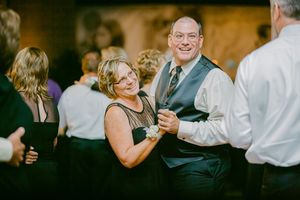 Dance partners move gracefully at an indoor event, with guests wearing formal attire and dancing in the warm lighting.