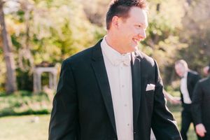 Happy couple laughing and celebrating together in elegant wedding attire in outdoor garden setting.
