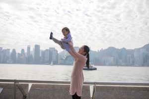 Family playfully posing by the water with city skyline visible in background.