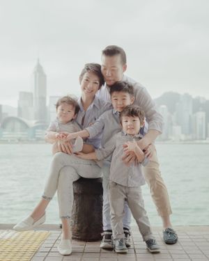 Family group posed by waterfront with city skyline creating scenic backdrop.