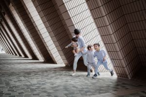 People walking through an architectural tunnel with dramatic angular lighting and shadows.