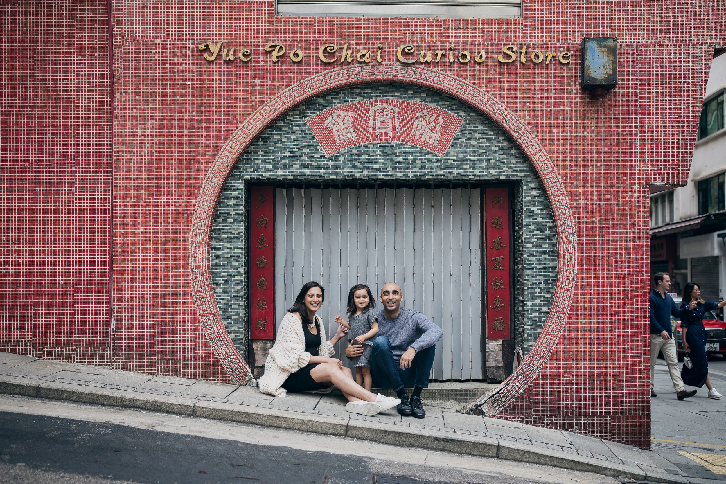 A group sits in a circular doorway of a red brick building in an urban setting.