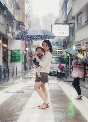 People dancing and playing in the rain with umbrellas on city street.