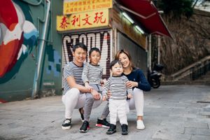 A family in coordinated striped outfits sits together on steps with Chinese characters in background.