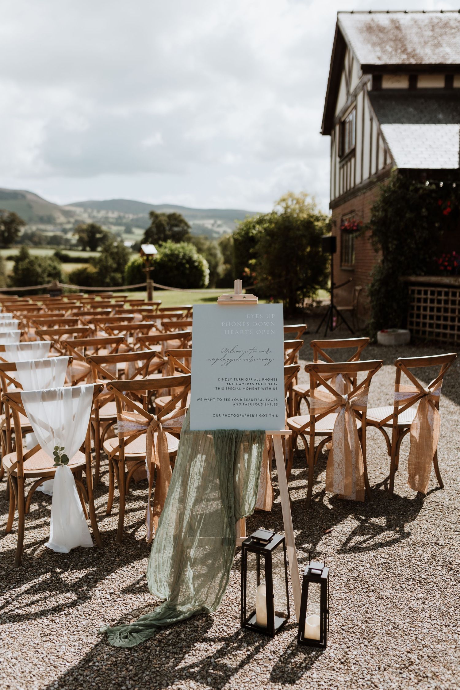 Rustic wooden cross-back chairs arranged in rows for an outdoor wedding ceremony with shadow patterns and natural lighting.