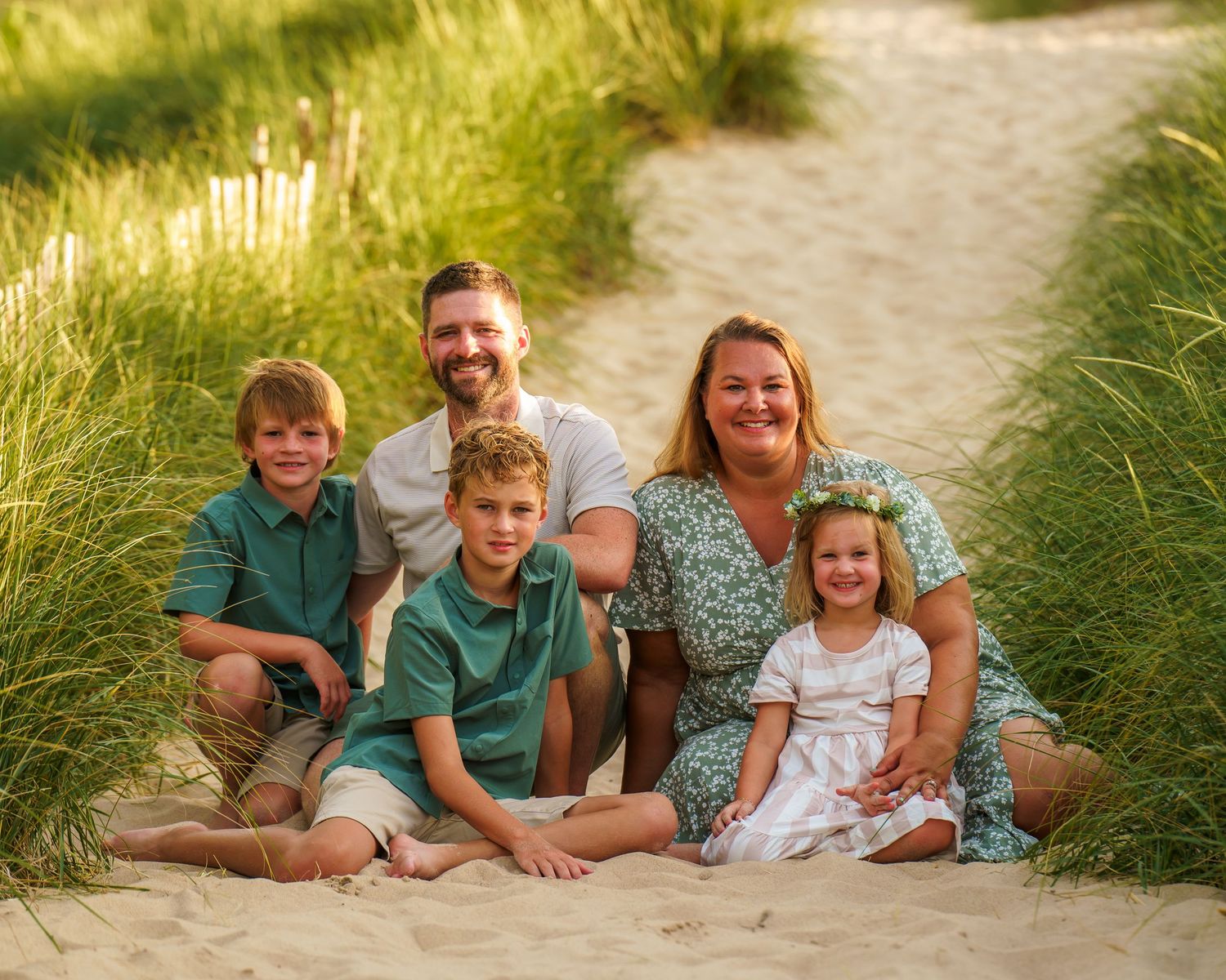 People relaxing in tall beach grass during a sunset photo session at a sandy beach location.