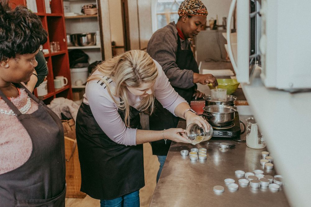 Guest pouring natural oils into a lip balm mold during the workshop