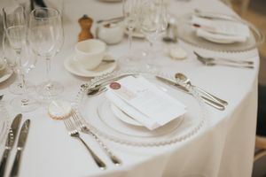Elegant white table setting with formal place settings, crystal glasses, and silver cutlery on a crisp white tablecloth.